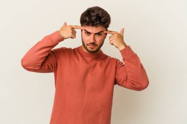 Beyaz arka planda izole edilmiş genç beyaz bir adam bir göreve odaklanmış, işaret parmaklarını işaret ediyor..