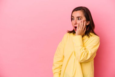 Pembe arka planda izole edilmiş orta yaşlı beyaz bir kadın gördüğü bir şey yüzünden şoka uğruyor..