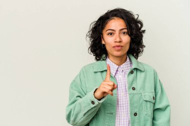 Beyaz arka planda izole edilmiş genç kıvırcık Latin kadın parmaklarıyla bir numarayı gösteriyor..