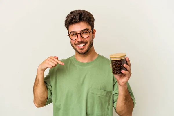 白地に隔離されたコーヒー瓶を手でシャツのコピースペースを指している若い白人男性 誇りと自信 — ストック写真