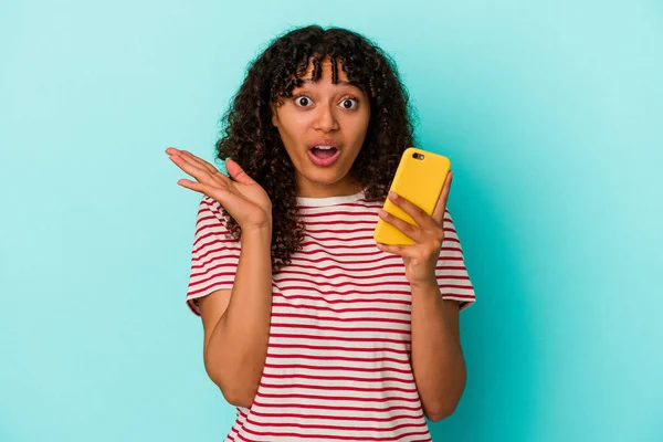 Ung Blandras Kvinna Som Håller Mobiltelefon Isolerad Blå Bakgrund Förvånad — Stockfoto