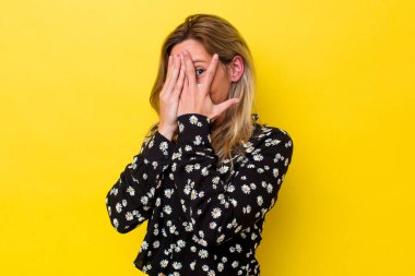 Avustralyalı genç bir kadın parmaklarının arasından korkmuş ve gergin bir şekilde göz kırpıyor..