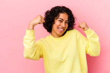 Pembe arka planda izole edilmiş genç kıvırcık Latin kadın zaferden sonra yumruğunu kaldırıyor, kazanan konsept..