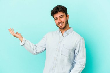 Mavi arka planda izole edilmiş beyaz bir genç hoş bir yüz ifadesi sergiliyor..