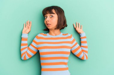 Genç melez kadın, mavi üzerine izole edilmiş, yaklaşan bir tehlike nedeniyle şoka uğruyor.