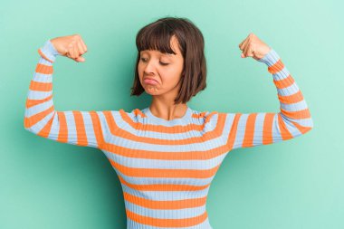 Mavi üzerine izole edilmiş genç bir ırk kadını güçlü bir jest yapıyor, kollarıyla, kadınsı gücün sembolü.