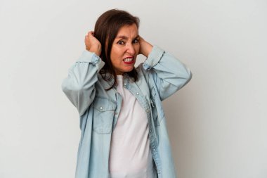 Beyaz arka planda izole edilmiş orta yaşlı beyaz kadın kulaklarını elleriyle kapatıyor..