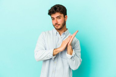 Kafkasyalı genç adam mavi arka planda izole edilmiş enerjik ve rahat hissediyor, ellerini ovuşturuyor kendinden emin.