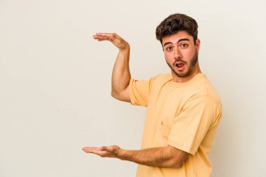 Beyaz arka planda izole edilmiş genç beyaz adam elleri arasında bir kopya alanı tutarken şok ve hayrete düştü..