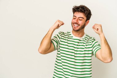 Beyaz arka planda izole edilmiş genç beyaz bir adam zaferden sonra yumruğunu kaldırıyor, kazanan konsept.