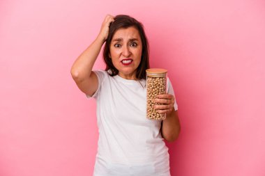 Pembe arka planda izole edilmiş nohut kavanozu tutan orta yaşlı beyaz bir adam şok geçiriyordu..