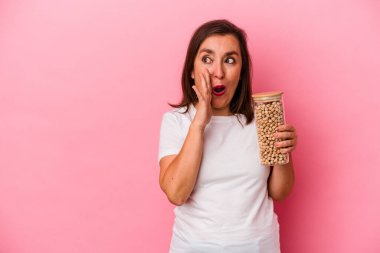 Pembe arka planda izole edilmiş nohut kavanozu tutan orta yaşlı beyaz bir adam gizli bir sıcak fren haberi veriyor ve yan bakıyor.