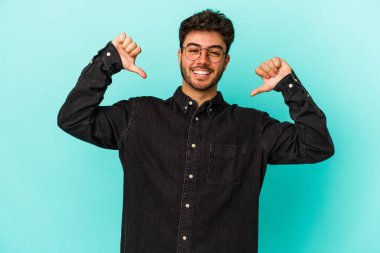 Mavi arka planda izole edilmiş genç beyaz adam gururlu ve kendinden emin hissediyor, örnek olarak.