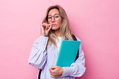 Avustralyalı genç bir öğrenci pembe arka planda izole edilmiş, parmakları dudaklarında bir sır saklıyor..