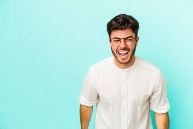 Kafkasyalı genç adam mavi arka planda izole edilmiş. Çok kızgın, öfkeli, hayal kırıklığına uğramış..