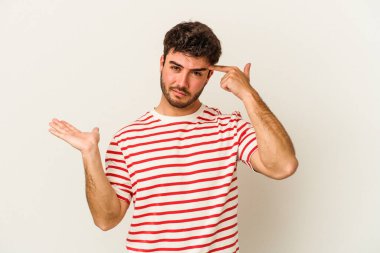 Beyaz arka planda izole edilmiş genç beyaz bir adam elinde bir ürün tutuyor ve.