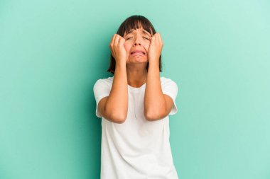 Genç melez kadın mavi üzerine izole edilmiş ağlayan, bir şeyden mutsuz, acı ve kafa karışıklığı konsepti..