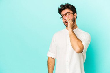 Mavi arka planda izole edilmiş genç beyaz bir adam gizli bir sıcak fren haberi veriyor ve yana bakıyor.