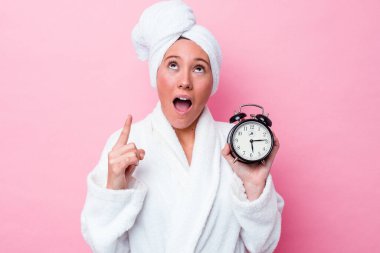 Genç Avustralyalı kadın duştan geç çıkıyor. Pembe arka planda tek başına. Ağzı açık, üst tarafı işaret ediyor..