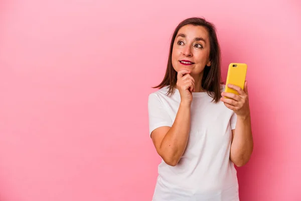 Medelålders Kaukasiska Kvinna Som Håller Mobiltelefon Isolerad Rosa Bakgrund Tittar — Stockfoto