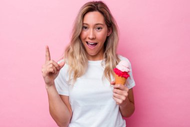 Genç Avustralyalı bir kadın pembe arka planda izole edilmiş bir dondurma tutuyor. Bir fikri, ilham verici bir fikri var..