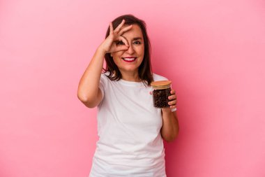 Elinde kahve kavanozu tutan orta yaşlı beyaz bir kadın pembe arka planda izole edilmiş..