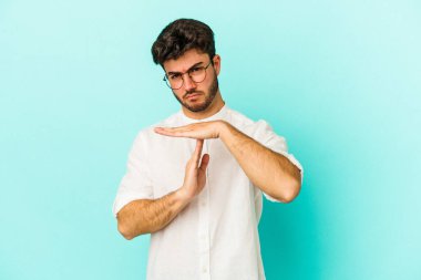 Mavi arka planda izole edilmiş genç beyaz bir adam bir mola hareketi gösteriyor..