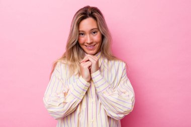 Avustralyalı genç bir kadın yalnız, elleri çenesinin altında, mutlu bir şekilde yan tarafa bakıyor..