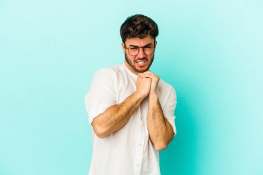 Kafkasyalı genç adam mavi arka planda izole edilmiş korkmuş ve korkmuş..