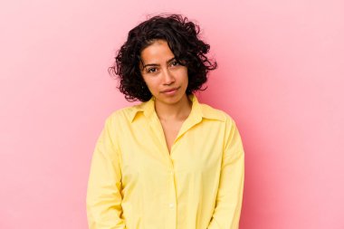 Genç kıvırcık Latin kadın pembe arka planda izole edilmiş üzgün, ciddi yüzlü, mutsuz ve hoşnutsuz.