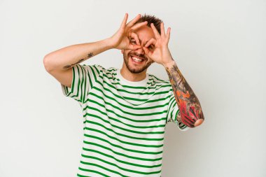 Beyaz arka planda izole edilmiş genç dövmeli beyaz bir adam gözlerde sorun olmadığını gösteriyor.