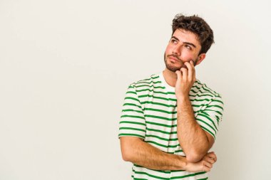 Beyaz arka planda izole edilmiş genç beyaz bir adam rahatlamış bir şeyin fotokopi odasına baktığını düşünüyor..