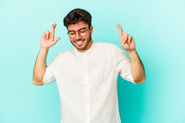 Kafkasyalı genç adam mavi arka planda izole edilmiş şans dilemek için şans diliyor.