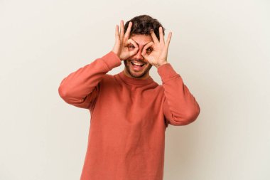 Beyaz arka planda izole genç beyaz adam heyecanlı tamam göz jesti tutmak.