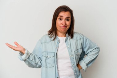 Beyaz arka planda soyutlanmış orta yaşlı beyaz bir kadın sorgulama sırasında omuz silkiyor ve şüphe duyuyor..