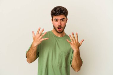 Beyaz arka planda izole edilmiş beyaz tenli genç adam on numarayı elleriyle gösteriyor..