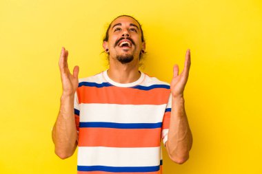 Sarı arka planda uzun saçlı beyaz bir adam elini göğsüne koyduğunda kahkahalarla gülüyor..