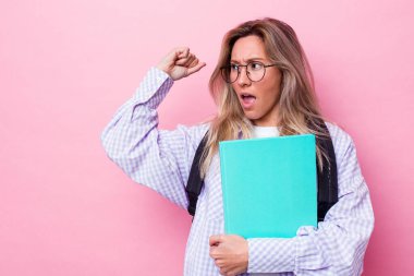 Genç Avustralyalı bir öğrenci pembe arka planda izole edilmiş zafer ve galibiyet kavramından sonra yumruğunu kaldırıyor..