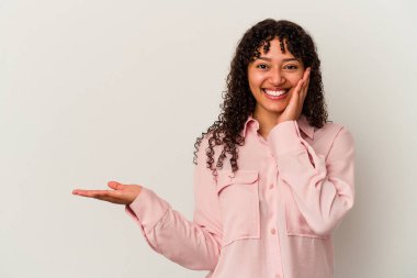 Beyaz arka planda izole edilmiş genç melez kadın avuç içinde fotokopi alanı tutuyor, el üstünde tutuyor. Şaşırmış ve mutlu..