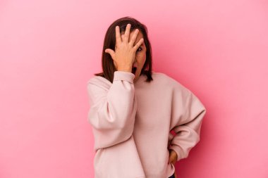 Pembe arka planda izole edilmiş orta yaşlı beyaz kadın yüzünün yarısını palmiye ile örterek eğleniyor..