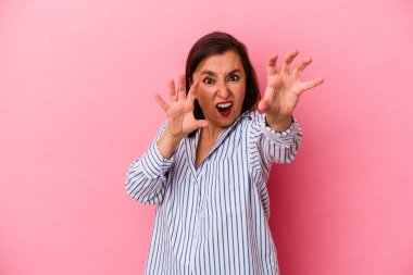 Pembe arka planda izole edilmiş orta yaşlı beyaz kadın gergin elleriyle çığlık atıyor..