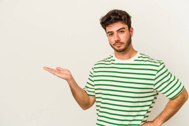 Beyaz arka planda izole edilmiş genç beyaz bir adam bir palmiye üzerinde fotokopi alanı gösteriyor ve belinde başka bir el tutuyor..