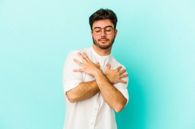 Kafkasyalı genç adam mavi arka planda izole edilmiş, güler yüzlü ve mutlu..