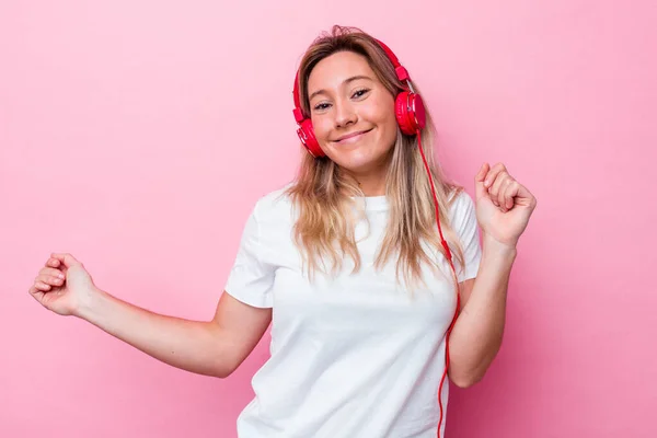 若いオーストラリア人女性はピンクの背景に隔離された音楽を聞いて — ストック写真