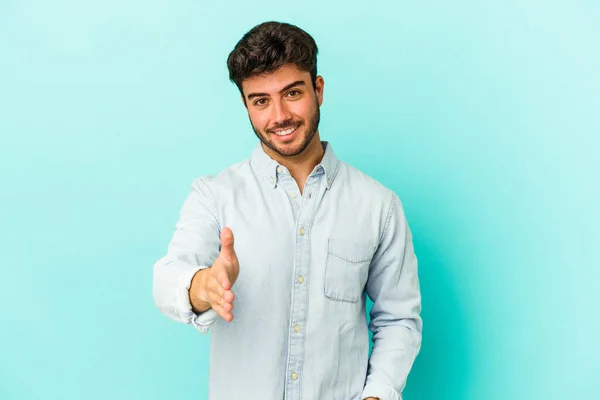 Jonge Blanke Man Geïsoleerd Blauwe Achtergrond Stretching Hand Camera Groet — Stockfoto