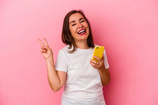 Medelålders Kaukasiska Kvinna Som Håller Mobiltelefon Isolerad Rosa Bakgrund Glad — Stockfoto