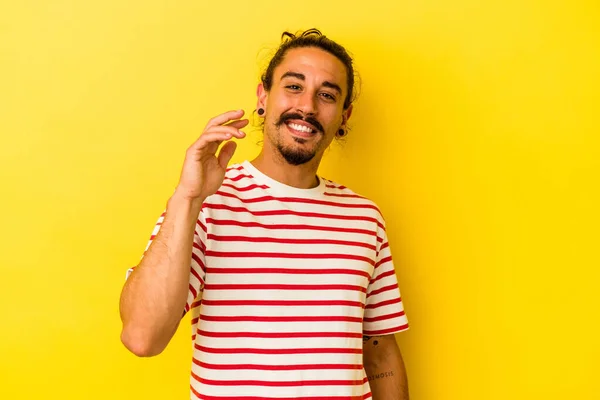 黄色の背景に長い髪の若い白人男性は何かについて笑って 手で口をカバー — ストック写真