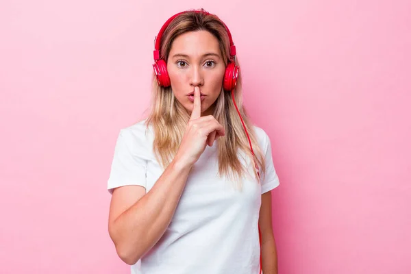 Young Australian Woman Listening Music Isolated Pink Background Keeping Secret — Stock Photo, Image