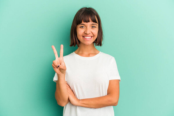 Молодая женщина смешанной расы, изолированная на синем, показывает номер два с пальцами.