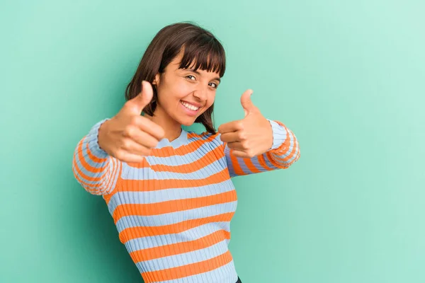 若い混合人種の女性は 両方の親指を上げ青い上に隔離されました 笑顔と自信 — ストック写真